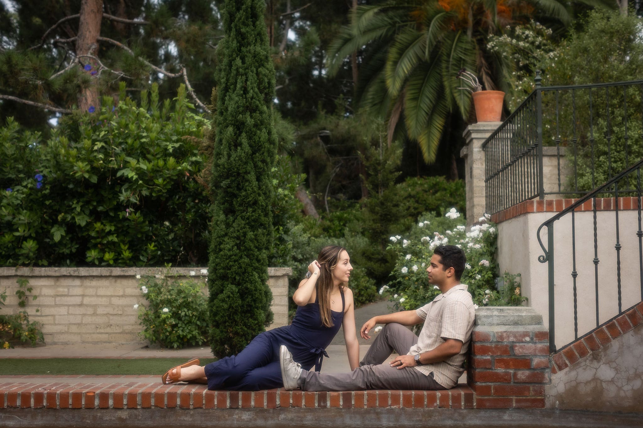 A happy couple lounge in a garden in blue and grey while chatting and smiling at each other after a couples massage in san diego